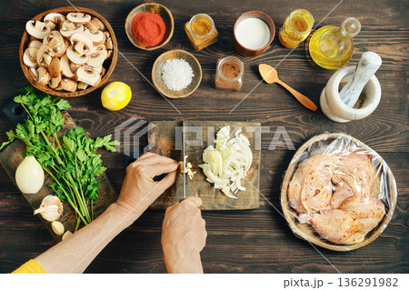 Top view of hands chopping fresh garlic on a wooden cutting board 136291982
