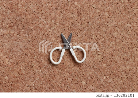 コルク背景に置かれた小さなハサミ 生活用品のミニマル素材写真 136292101