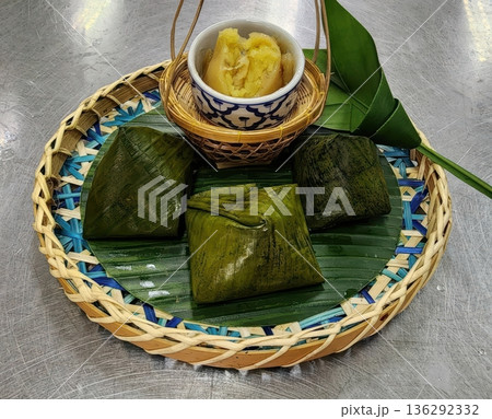 Traditional Thai Steamed Desserts Wrapped in Banana Leaves on Woven Tray Traditional Thai Steamed Desserts Wrapped in Banana Leaves on Woven Tray 136292332