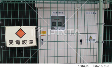 フェンス越しに設置された屋外の受電設備と高電圧危険の警告看板 フェンス越しに設置された屋外の受電設備と高電圧危険の警告看板 136292508