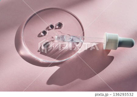 Clear cosmetic serum dropper and droplets on glass petri dish Clear cosmetic serum dropper and droplets on glass petri dish 136293532