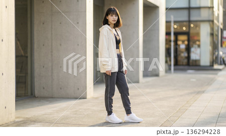 街中でスポーツウェアを着て佇む健康的な日本人女性の全身写真 136294228