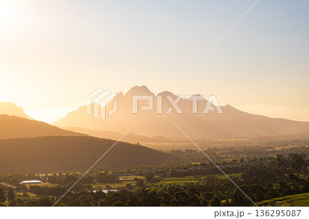 Simonsberg mountain panorama at sunset. Golden hour glow over picturesque Stellenbosch valley with vineyards. South Africa travel and nature beauty. 136295087