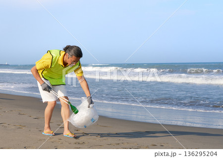 海岸でボランティアとしてゴミ拾い活動に励むシニアの日本人男性 136295204