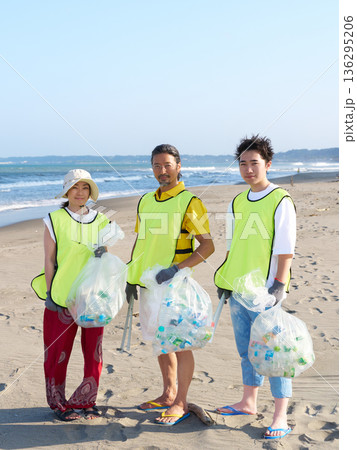 ビーチクリーンで集めたゴミ袋を持ってカメラを見るボランティアのグループ 136295206
