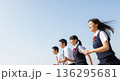 青空の下を笑顔で走る4人の高校生男女。左側に広い余白のある、青春や未来をイメージした広告用素材。 136295681