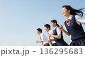 青空の下を笑顔で走る男女高校生。左側に広い余白のある、青春や未来をイメージした爽やかな広告用素材。 136295683