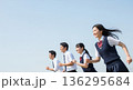 青空の下を笑顔で走る4人の男女高校生。左側に広い余白のある、青春や未来をイメージした広告用素材。 136295684