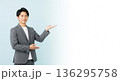笑顔で案内するスーツ姿の男性ビジネスパーソン。右側に広い余白のある、汎用性の高い広告用イメージ。 136295758