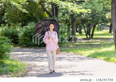 日傘をさして散歩する笑顔の女性 日傘をさして散歩する笑顔の女性 136295789