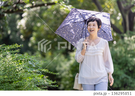 日傘をさしている笑顔のミドル女性 日傘をさしている笑顔のミドル女性 136295851
