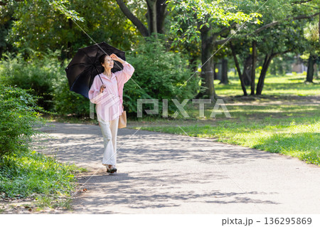 日傘をさして散歩する笑顔の女性 136295869