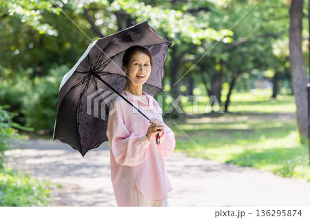 日傘をさして散歩する笑顔の女性 日傘をさして散歩する笑顔の女性 136295874