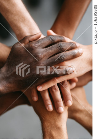 A close-up of multiple diverse hands stacked on top of each other, symbolizing unity, support, and strength within a cohesive team. 136295988