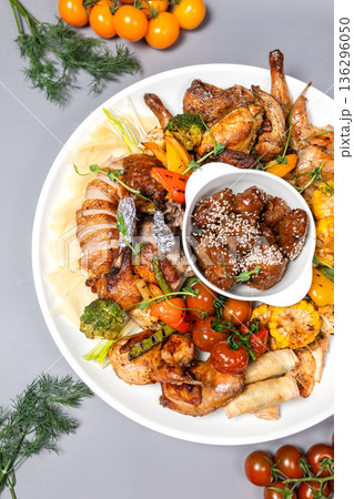 Top view of chicken platter with vegetables and sauce on white plate 136296050