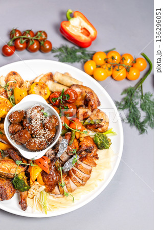 Top view of chicken platter with vegetables sauces and decorative elements on grey background 136296051