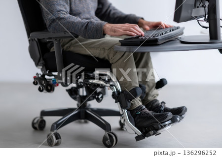Man in adaptive chair working at computer 136296252