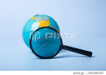 Globe and magnifying glass exploring global research 136296354