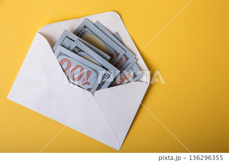 Hundred dollar bills in white envelope on yellow background 136296355