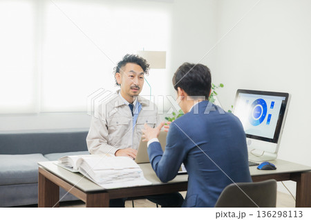会社で資料を見ながら打ち合わせするエンジニア 136298113