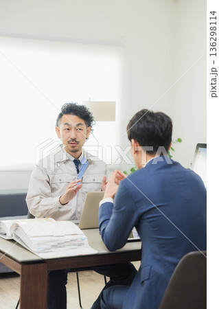 会社で資料を見ながら打ち合わせするエンジニア 136298114