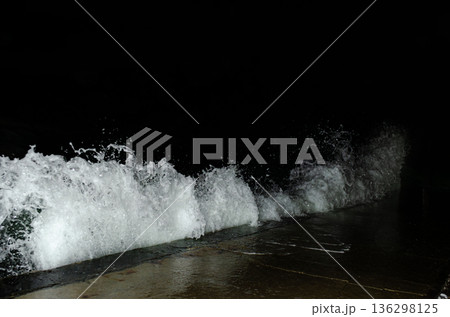 A powerful wave crashes, spraying white foam against darkness. A powerful wave crashes, spraying white foam against darkness. 136298125