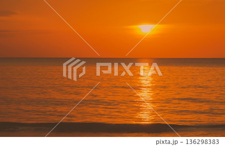 The sun sets over the Andaman Sea, casting an orange hue across the sky and water. The light reflects on the surface as day turns into night along the coastline. High quality photo The sun sets over the Andaman Sea, casting an orange hue across the sky and water. The light reflects on the surface as day turns into night along the coastline. High quality photo 136298383