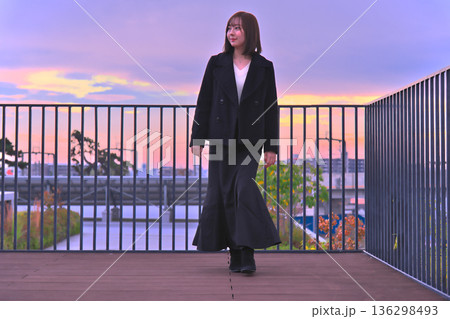 マジックアワーの夕焼け空を背景に、屋上のテラスで微笑む冬服姿の若い日本人女性のポートレート マジックアワーの夕焼け空を背景に、屋上のテラスで微笑む冬服姿の若い日本人女性のポートレート 136298493