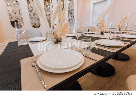 Elegant private dining table with pampas centerpieces, candles and modern tableware 136298762