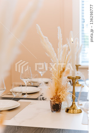Elegant pampas centerpiece with candle on modern dining table, soft neutral interior Elegant pampas centerpiece with candle on modern dining table, soft neutral interior 136298777