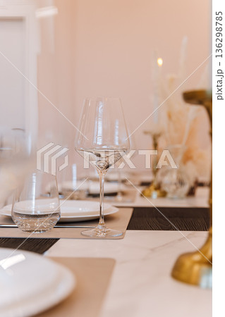 Elegant restaurant table setting with glassware, pampas decor and warm bokeh lighting Elegant restaurant table setting with glassware, pampas decor and warm bokeh lighting 136298785