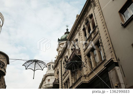 Historic buildings in Belgrade old town with decorative umbrellas hanging above the street, combining classic European architecture and creative urban street decoration 136299883