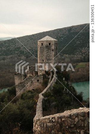 Stone wall path leading to the main tower of Pocitelj Fortress above the Neretva River in Bosnia and Herzegovina. Medieval fortifications and nature express strength and timeless travel concept Stone wall path leading to the main tower of Pocitelj Fortress above the Neretva River in Bosnia and Herzegovina. Medieval fortifications and nature express strength and timeless travel concept 136300451