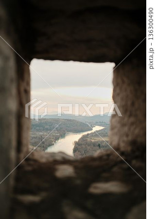 View through a stone window of Pocitelj Fortress overlooking the winding Neretva River and quiet valley landscape in southern Bosnia and Herzegovina View through a stone window of Pocitelj Fortress overlooking the winding Neretva River and quiet valley landscape in southern Bosnia and Herzegovina 136300490