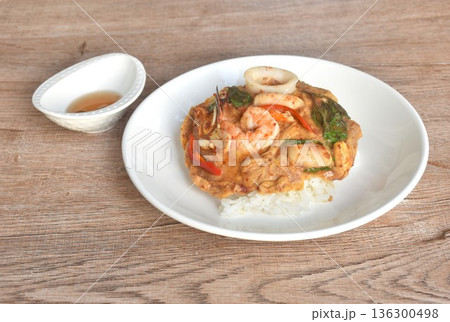 Thai steamed red Curry with seafood on cream egg omelet topping plain rice in plate 136300498