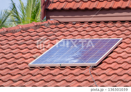 A Solar Panel Installed on a Red-Tiled Roof: Photovoltaic Cells Converting Sunlight into Electricity, a Key Renewable Energy Source for Sustainable Home Power. High quality photo 136301039