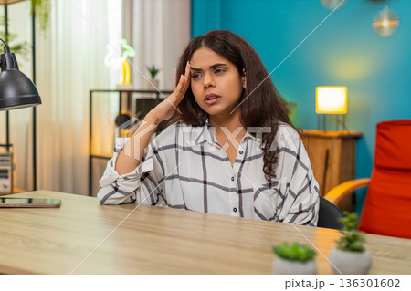 Indian woman holds head eyes closed grimacing pain strong severe headache health issue indoors home Indian woman holds head eyes closed grimacing pain strong severe headache health issue indoors home 136301602