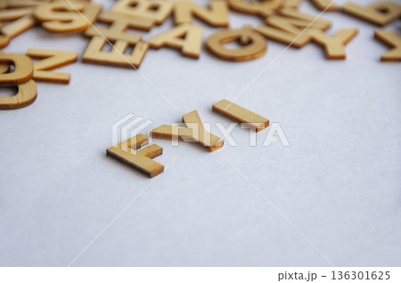 FYI text composed of wooden letters on white surface representing quick notice information sharing and workplace communication concept. 136301625