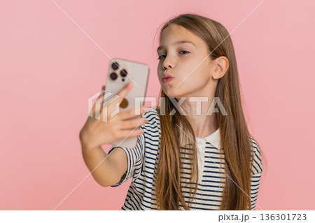 Child girl kid happily taking funny selfies on smartphone laughing joyfully making playful faces Child girl kid happily taking funny selfies on smartphone laughing joyfully making playful faces 136301723