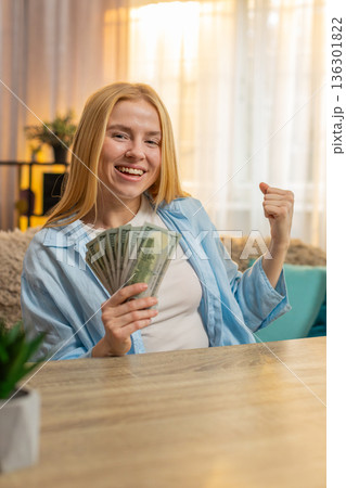 Young woman winning lottery at home table, money bundle, laughter, big joy, lucky moment, happy Young woman winning lottery at home table, money bundle, laughter, big joy, lucky moment, happy 136301822