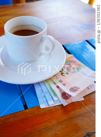 Coffee cup on table with yuan bill money in cafe. Payment coffee drink on breakfast. Yuan biill Coffee cup on table with yuan bill money in cafe. Payment coffee drink on breakfast. Yuan biill 136302362