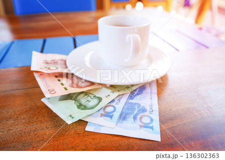 Coffee cup on table with yuan bill money in cafe. Payment coffee drink on breakfast. Yuan biill 136302363