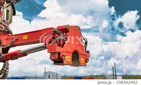 A drilling rig operates to extract oil and gas resources from the ground in a rural area under a bright blue sky with clouds 136302492