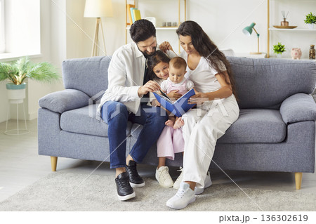 Mother and father reading an interesting book with their baby and daughter at home 136302619