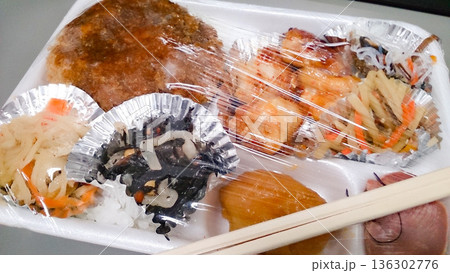 おかずが茶色のものが目立つラップがしてある弁当 おかずが茶色のものが目立つラップがしてある弁当 136302776