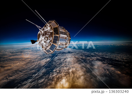 Detailed view of a satellite in space, featuring metallic structure, antennas, and large solar panels, orbiting above Earth's blue atmosphere and orange-tinted cloud layers against the dark void. 136303240