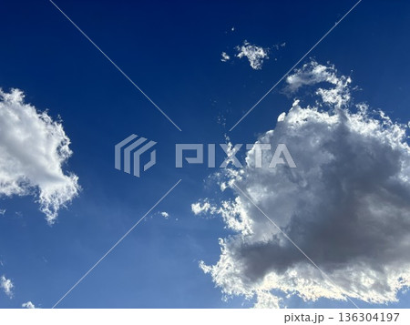 鮮やかな青空と白い雲のコントラスト 雲の裏側から強く差し込む太陽の光と美しい輝き 136304197