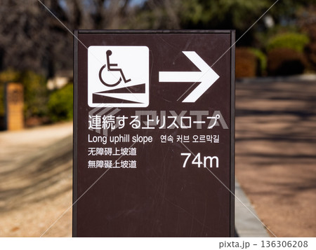 車椅子対応の長距離上り坂を示す多言語案内看板 136306208