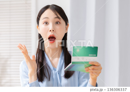 通帳を見て驚く女性 136306337