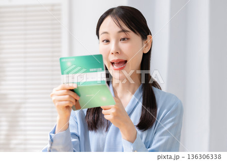 通帳を見て驚く女性 136306338